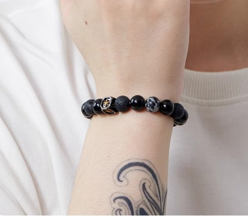 bracelet noir unisexe porté au poignet, perle étoile